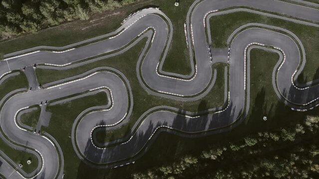 Aerial drone footage of a bird's-eye view of a race track. Empty racing field located near the forest.