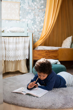 Boy studying while lying on rug at home