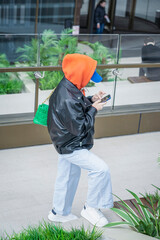 Unrecognizable young girl in jacket with hood using smartphone. Modern technology. Regular people,...