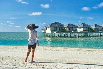 Paradise beaches of the Maldives. Tourism, travel and vacation in a luxury resort. Woman in bikini on the background of the sea and the beach