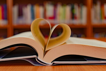 Close-up of an open book with its pages in the shape of a heart, on the table of a reading room in...