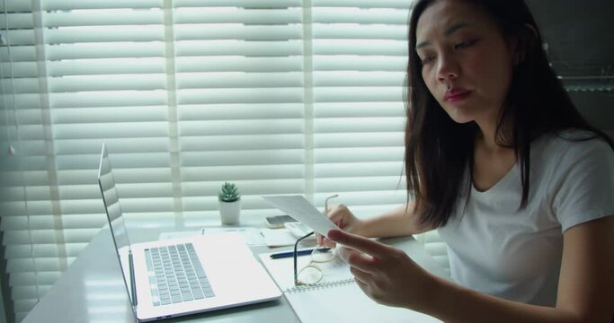 Stressed young woman Asian calculating monthly home expenses, tax, credit card bills payment and bank account balance not enough money to pay monthly.