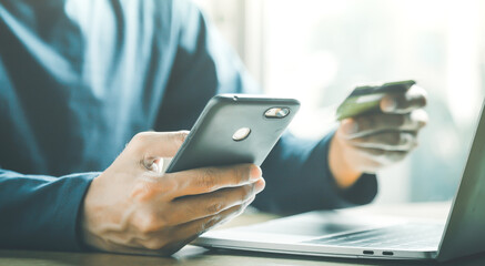Man holding credit card and using smartphone at home online shopping ecommerce internet banking spend money work from home concept.