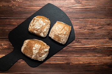 Homemade wholemeal bread rolls on one cutting board. Dark wooden table background, top view and space for text.