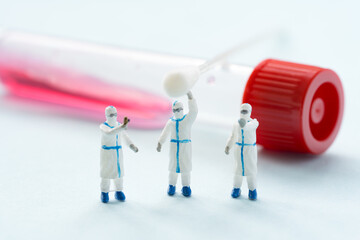 miniature doctors standing in front of tubes and cotton swab. COVID PCR test concept.