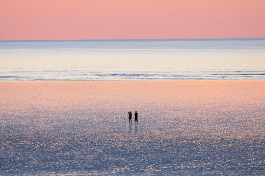A couple are enjoying the beautiful sunset view at 80 mile beach, in Broome, Western Australia