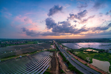 Solar panels on both sides of the highway in the sunset.