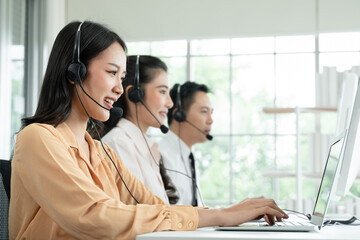 Group of Asian employee work in telemarketing customer service teams. Young operator woman working with headset smiling and doing customer support at work. Call Center with service mind concept