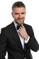 businessman fixing his bowtie and smiling at the camera