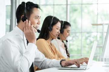 Group of Asian employee work in telemarketing customer service teams. Young operator man working with headset smiling and doing customer support at work. Call Center with service mind concept