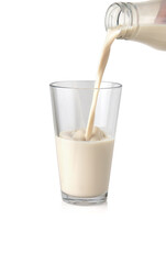 Milk pouring into the clear glass isolated on white background