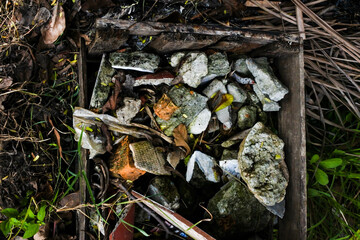 The badly damaged wooden crate is filled with rock debris and dried organic matter