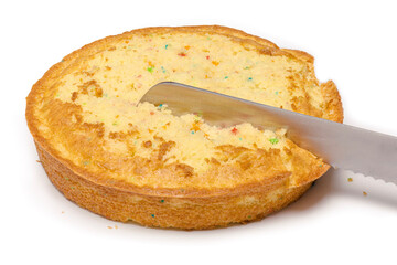 Knife slicing through confetti birthday cake isolated on white.