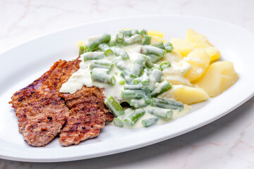 pork meat with cream sauce of green beans and cooked potatoes