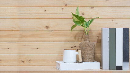 Books on wooden table with green leaf and wooden wall background empty copy space for text. minimal Workspace desk.