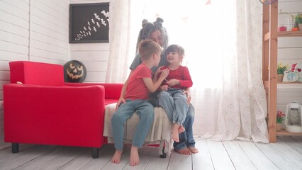 Children with their mother decorate the room for Halloween - 507824026
