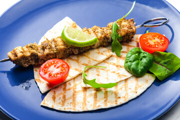 herbal meat skewer  with pita bread, tomatoes and lime