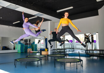 Four young women on trampoline, young fitness girls trains on   fitness studio.
