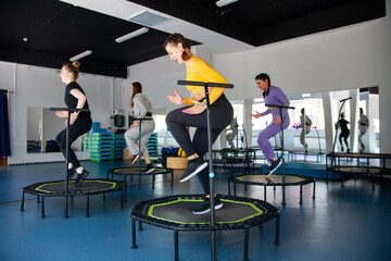 Group of happy women warming up before training in   gym jumping on   trampoline