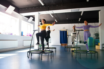 Group of happy women warming up before training in   gym jumping on   trampoline