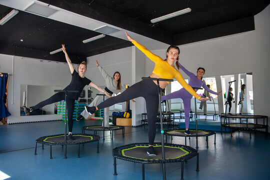 Four young women on trampoline, young fitness girls trains on   fitness studio.