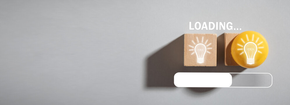 Idea loading concept with light bulb on wooden cube. Progress, creativity for business idea