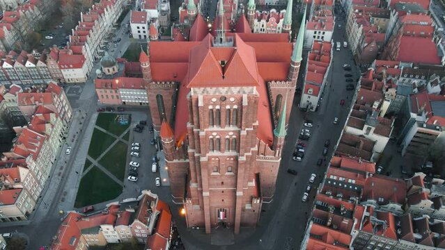 Aerial pull back tilt up shot of St. Mary's Church in old town of Gdańsk during sunset