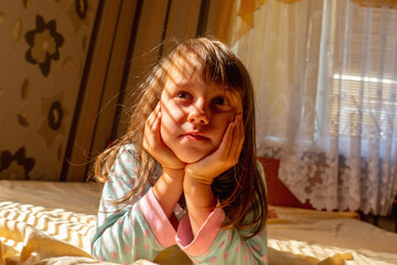 Happiness concept. Funny portrait of young beauutiful child girl wake up and smiling in morning sun rays.