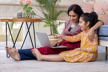 Mother and daughter using laptop at home