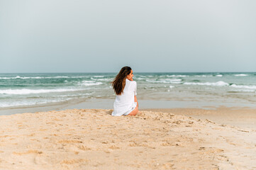 Happy woman sitting on sandy beach