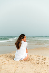 Fototapeta na wymiar Happy woman sitting on sandy beach