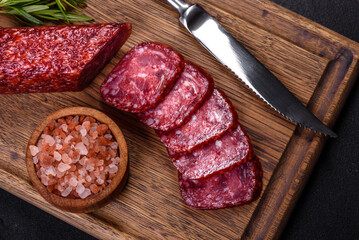 Smoked salami with rosemary, garlic and tomatoes on wooden cutting board