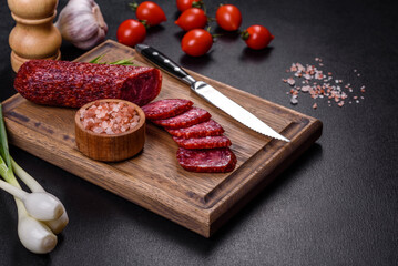 Smoked salami with rosemary, garlic and tomatoes on wooden cutting board