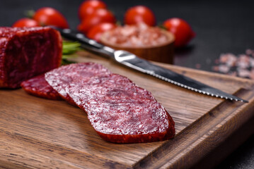 Smoked salami with rosemary, garlic and tomatoes on wooden cutting board