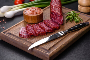 Smoked salami with rosemary, garlic and tomatoes on wooden cutting board