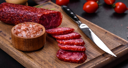 Smoked salami with rosemary, garlic and tomatoes on wooden cutting board