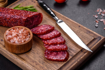 Smoked salami with rosemary, garlic and tomatoes on wooden cutting board