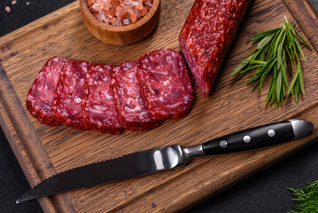 Smoked salami with rosemary, garlic and tomatoes on wooden cutting board