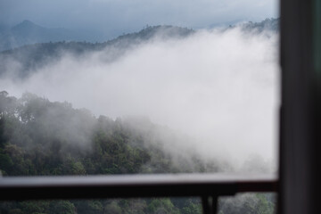 A wooden terrace with greenery rainforest mountains and hills on foggy day in background