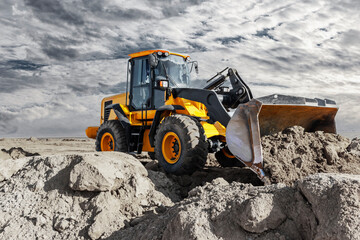Bulldozer or loader moves the earth at the construction site against the sunset sky. Contrasting image of a modern loader or bulldozer. Construction heavy equipment for earthworks.