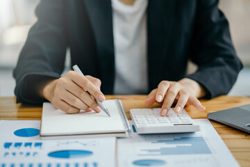 Obraz premium Close-up of businesswoman hands using a calculator to check company finances and earnings and budget. Business woman calculating monthly expenses, managing budget, papers, loan documents, invoices.