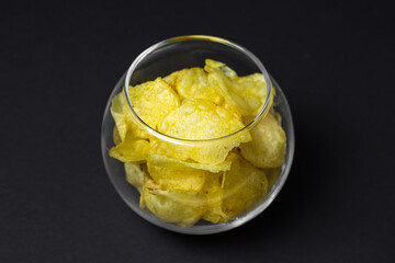Potato chips on a black background. Delicious snack for beer and other drinks.