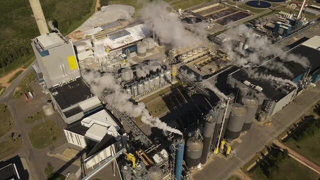 A dynamic aerial footage tilting downward towards the UPM Fray Bentos pulp mill factory located on the banks of the River Uruguay. The mill produces bleached hardwood eucalyptus pulp.