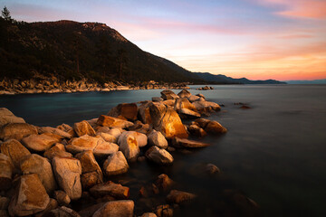 Boulders in Lake Tahoe in late sunset light featuring warm tones in clouds.  Photographed between King's Beach and Sand Harbor in Nevada. - obrazy, fototapety, plakaty