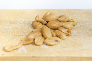 Salted peanuts peeled separately on a wooden table.