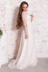 Fototapeta na wymiar Bride in a white dress against a brick wall.