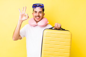young hispanic man feeling happy, showing approval with okay gesture. travel concept