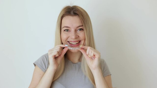 Smiling girl putting transparent aligner in teeth