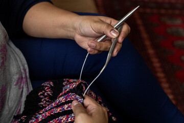 Close-up of Latin American woman's hands holding a type of circular needles ideal for knitting long lengths in the round with wool material yarns, Concept hobby, leisure activity