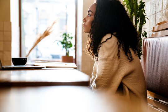 Young black woman working with laptop while sitting in cafe